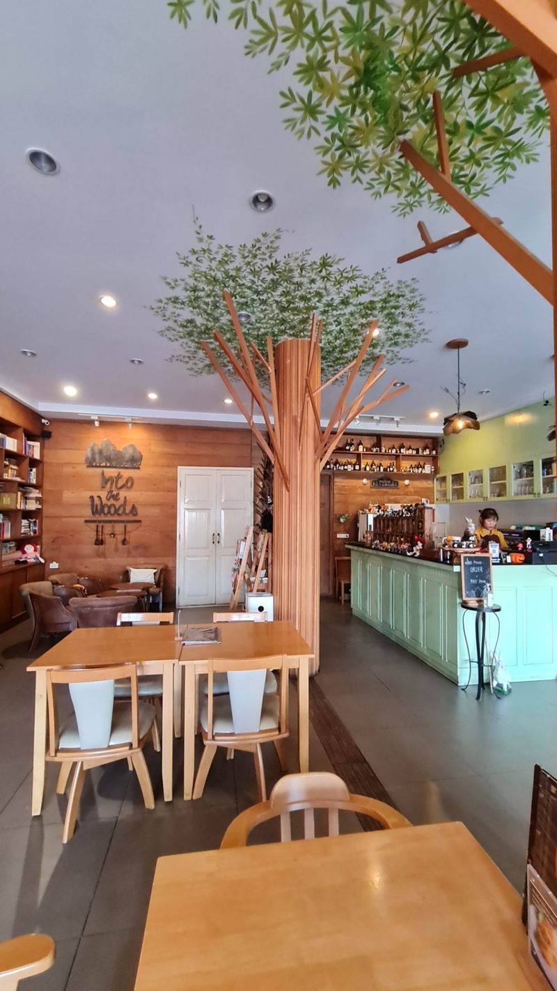 Warm tree-filled interior of Into the Woods Cafe in Chiang Mai